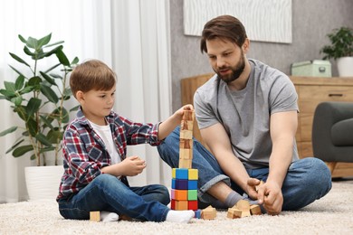 Photo of Dad and son building tower with cubes at home