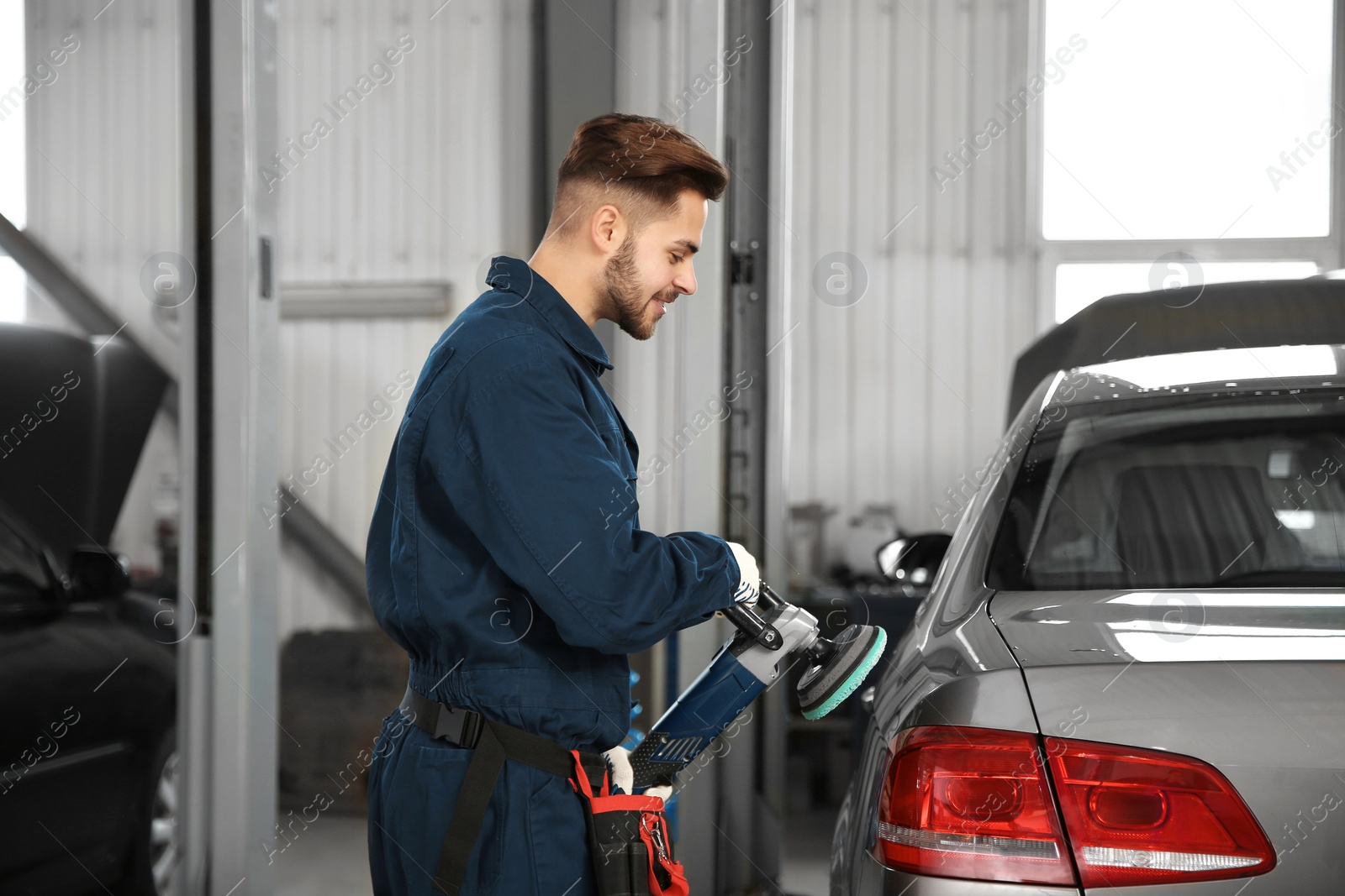 Photo of Technician polishing car body with tool at automobile repair shop