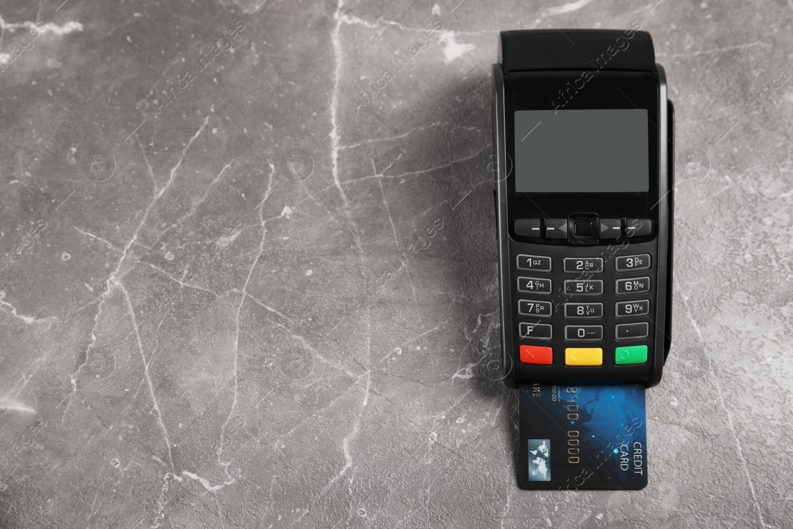 Photo of Modern payment terminal with credit card on grey background, top view. Space for text