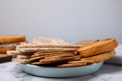 Photo of Rye crispbreads, rice cakes and rusks on white marble table, space for text
