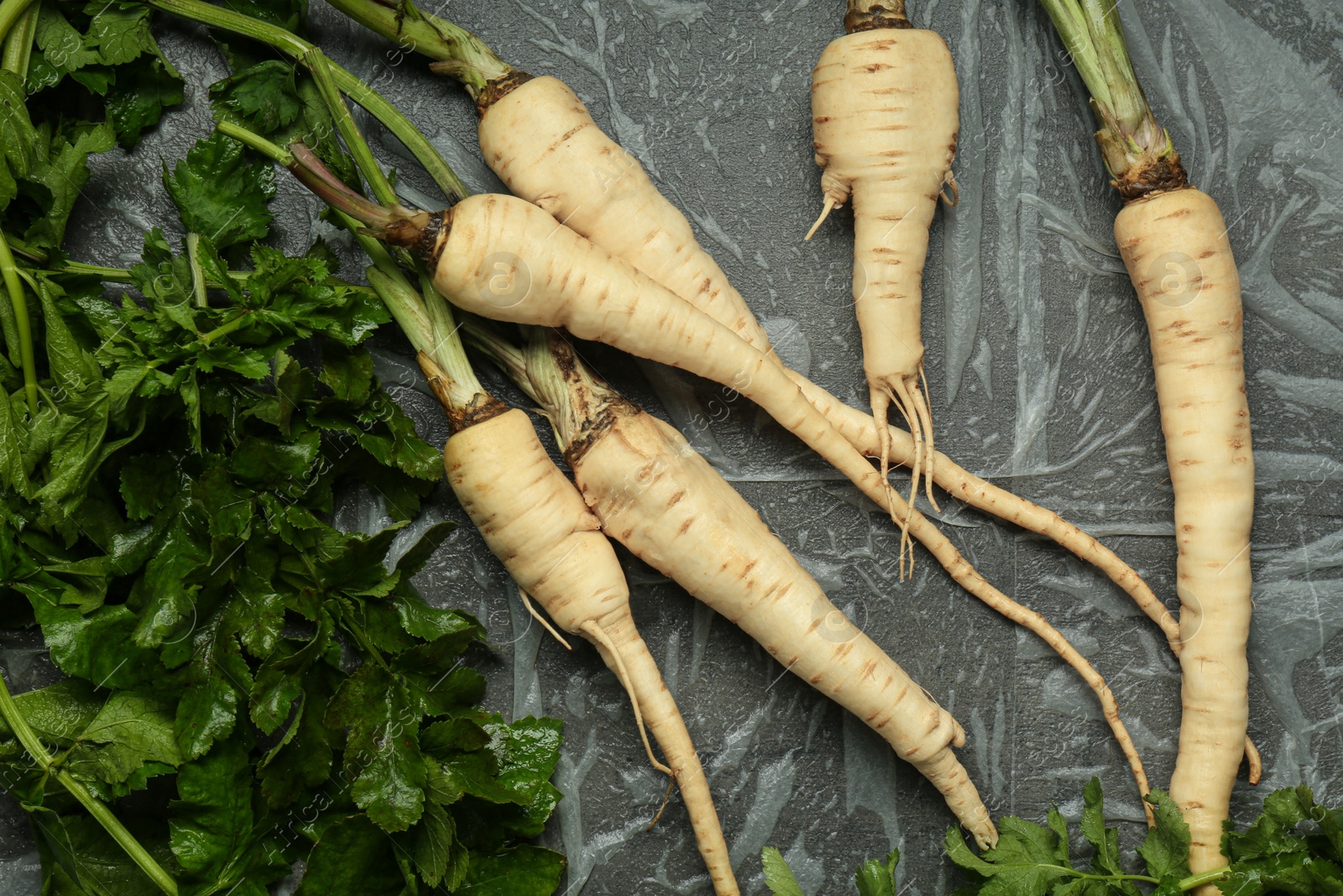 Photo of Tasty fresh ripe parsnips on grey table, flat lay