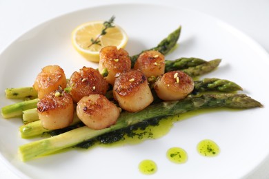 Delicious fried scallops with asparagus, lemon and thyme on white background, closeup