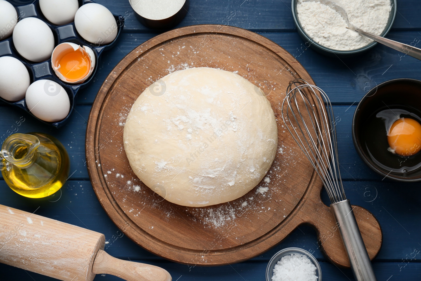 Photo of Fresh yeast dough and ingredients on blue wooden table, flat lay