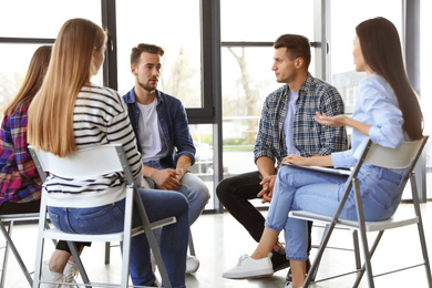 Photo of Psychotherapist working with patients in group therapy session indoors