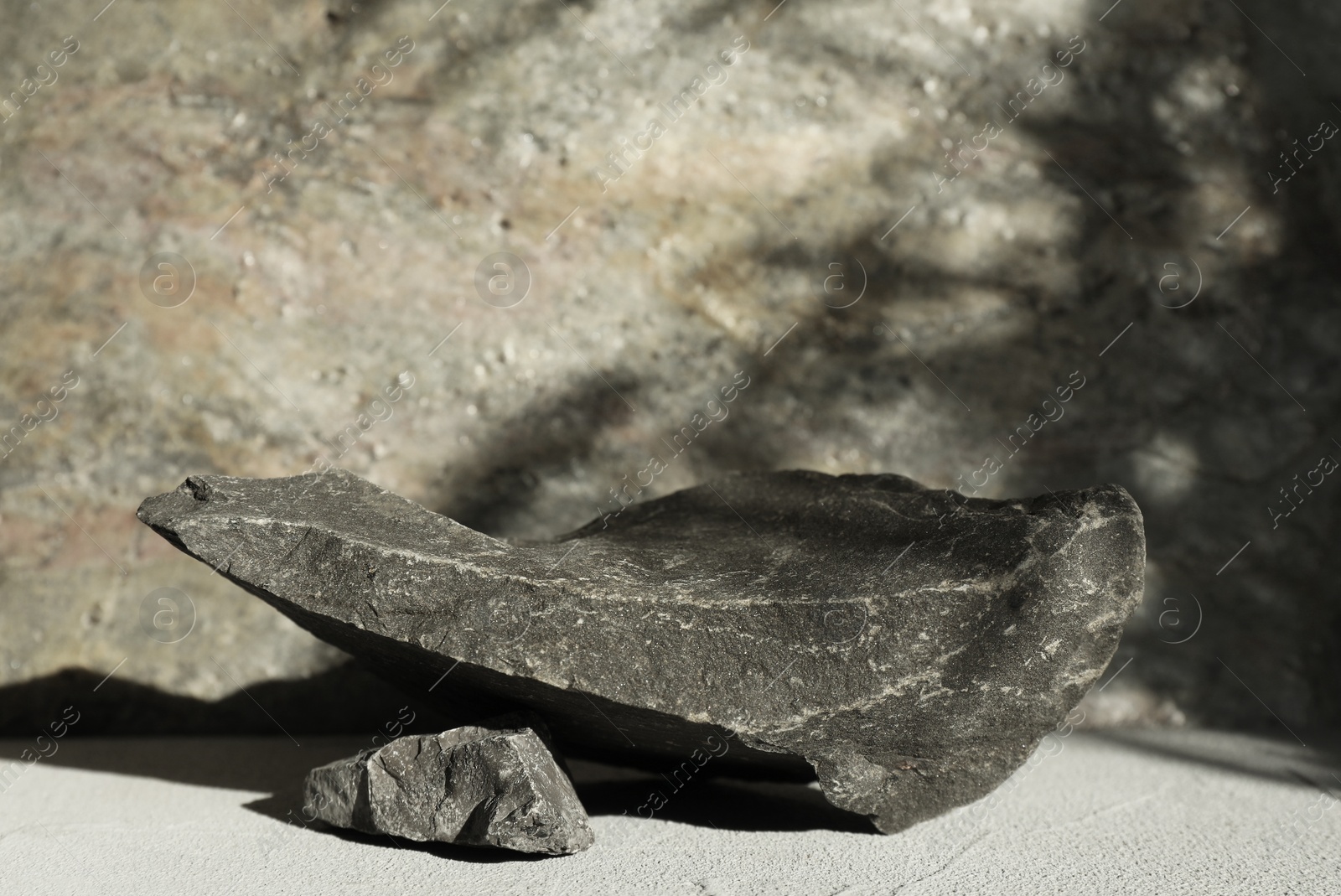 Photo of Presentation of product. Podium made of stones on light textured table. Space for text