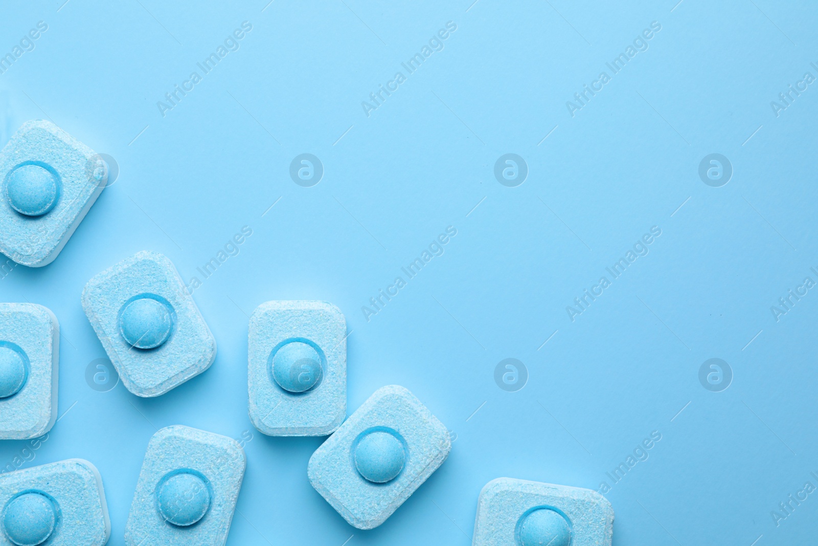 Photo of Water softener tablets on light blue background, flat lay. Space for text