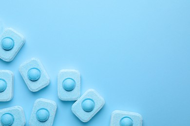 Photo of Water softener tablets on light blue background, flat lay. Space for text