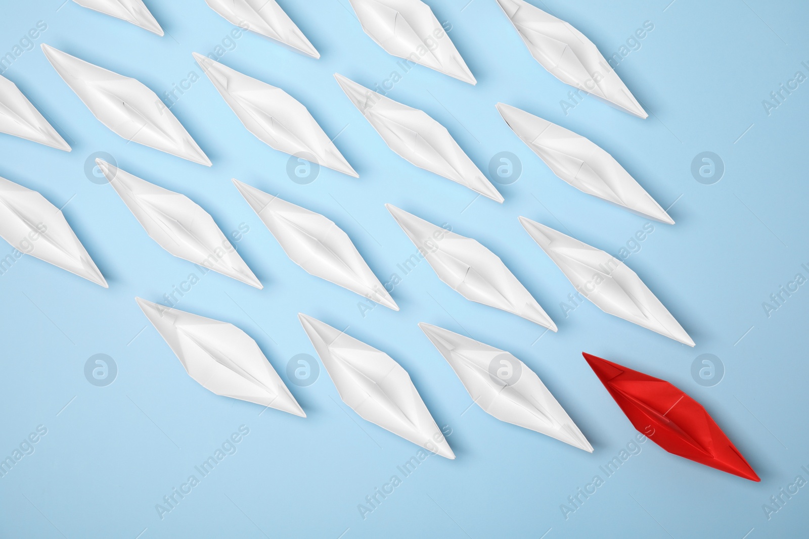 Photo of Paper boats following red one on light blue background, flat lay. Leadership concept