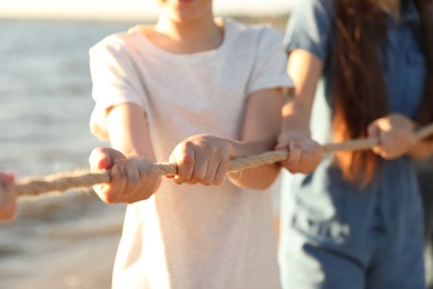 Children pulling rope during tug of war game outdoors, closeup. Summer camp