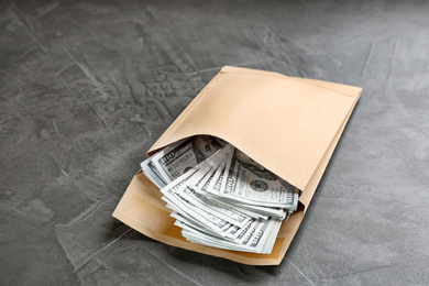 Envelope with dollar bills on grey stone table. Bribe concept