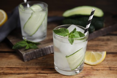 Glasses of refreshing cucumber water with mint on wooden table