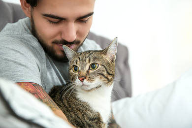 Photo of Man with cat on bed at home. Friendly pet
