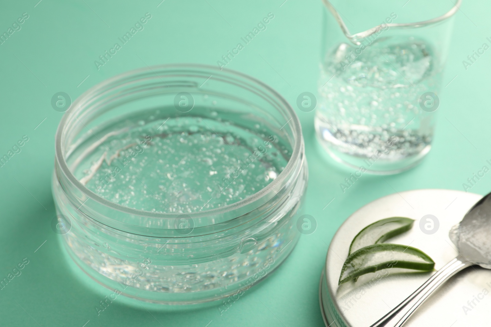 Photo of Jar of cosmetic gel and aloe on turquoise background