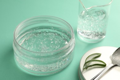 Photo of Jar of cosmetic gel and aloe on turquoise background