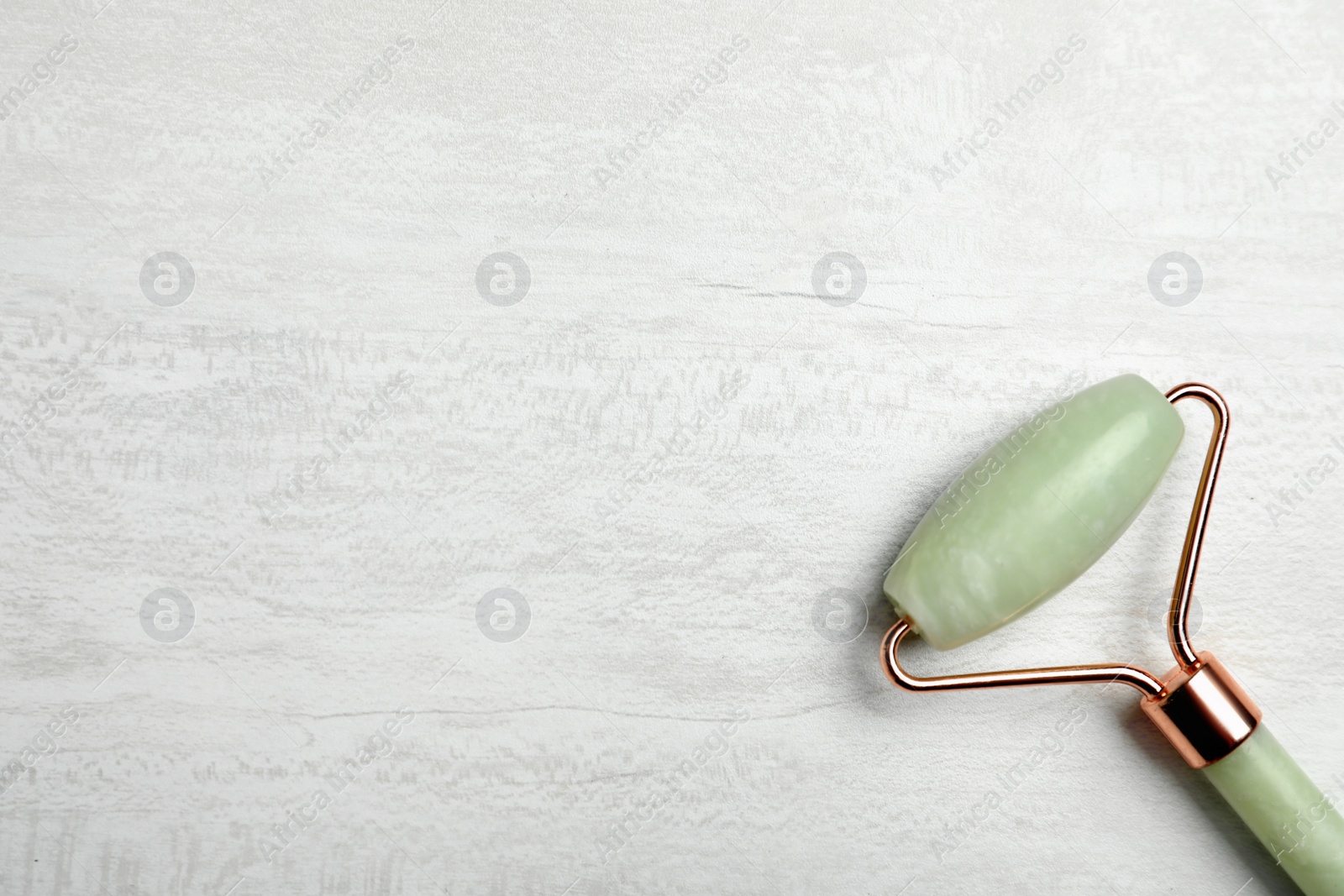 Photo of Natural jade face roller on light background, top view. Space for text