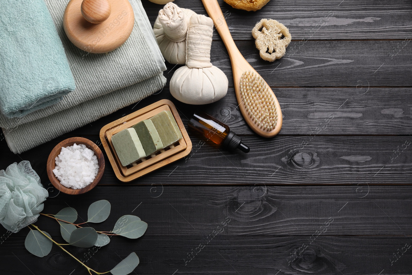 Photo of Flat lay composition with different spa products and eucalyptus branches on black wooden table. Space for text