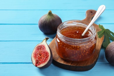 Jar of tasty sweet jam and fresh figs on light blue wooden table, closeup. Space for text