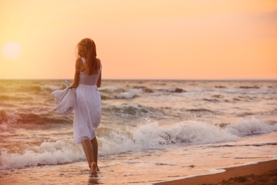 Photo of Beautiful young woman on beach at sunset