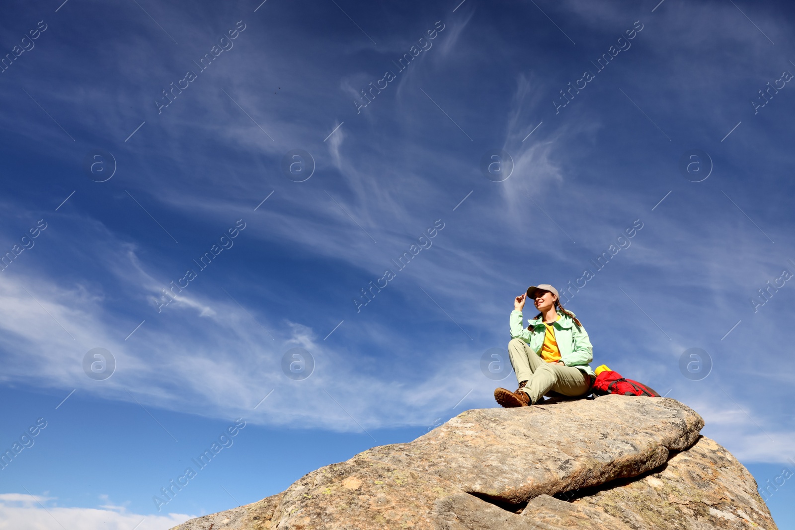 Photo of Tourist with backpack on cliff in mountains, low angle view
