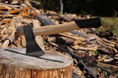 Photo of Tree stump with axe and cut firewood outdoors