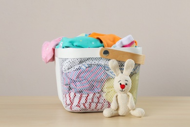 Photo of Laundry basket with different children's clothes and toy on wooden table