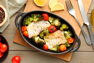 Photo of Tasty cod cooked with vegetables served on wooden table, flat lay