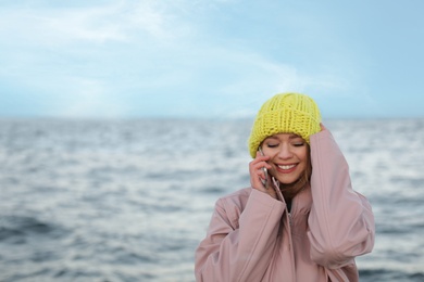 Young woman talking on mobile phone near sea