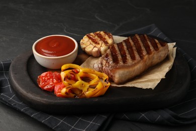 Photo of Delicious grilled beef steak with spices and tomato sauce on dark table