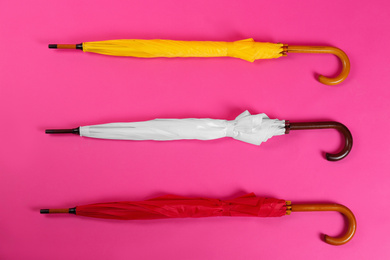 Photo of Colorful umbrellas on pink background, flat lay