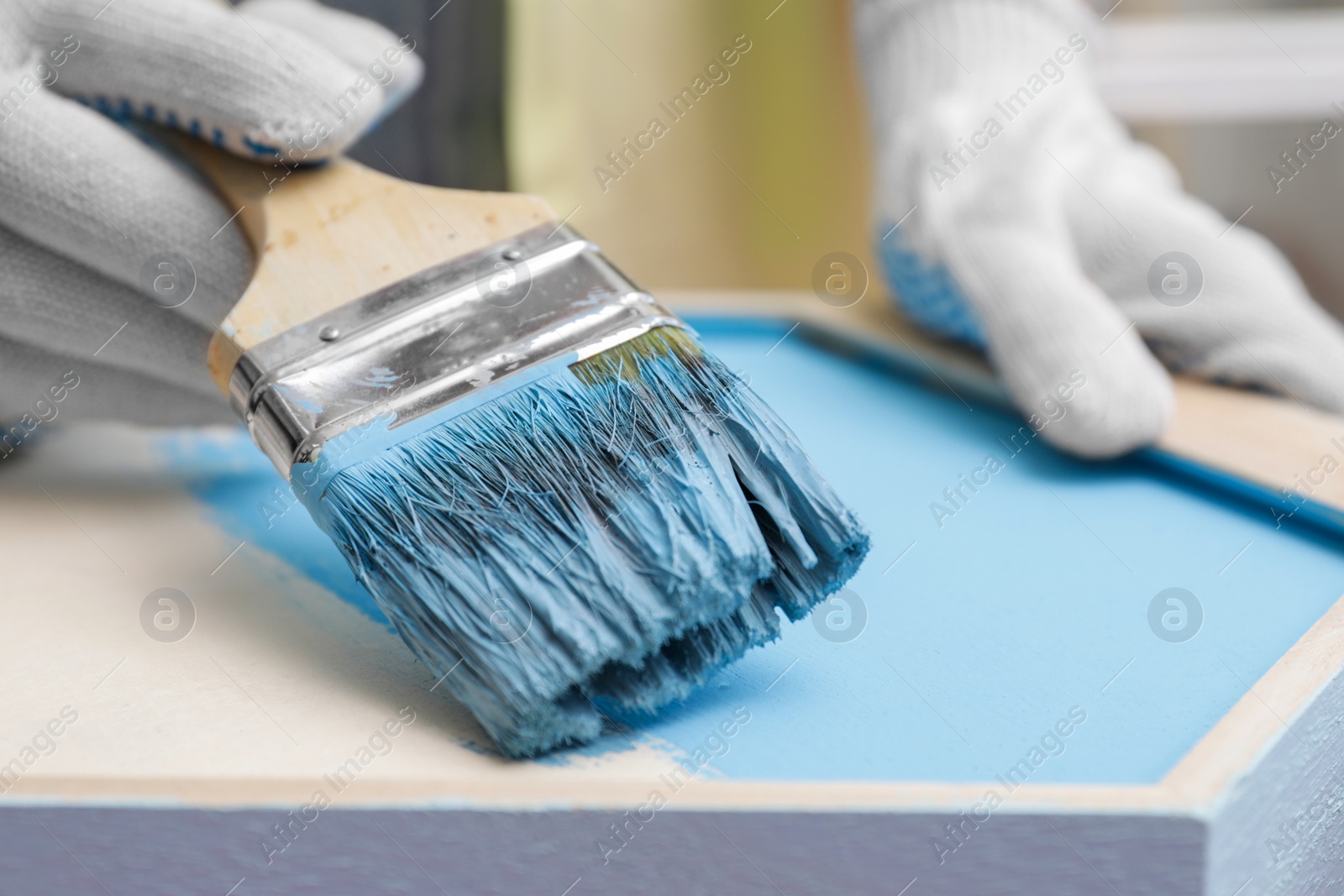 Photo of Woman painting honeycomb shaped shelf with brush, closeup
