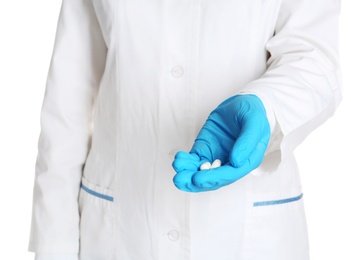 Photo of Doctor in medical glove holding pills on white background