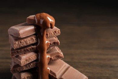Photo of Pieces of milk chocolate with tasty paste on blurred background, closeup. Space for text