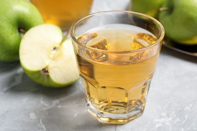 Photo of Glass of fresh juice and apples on grey table, closeup