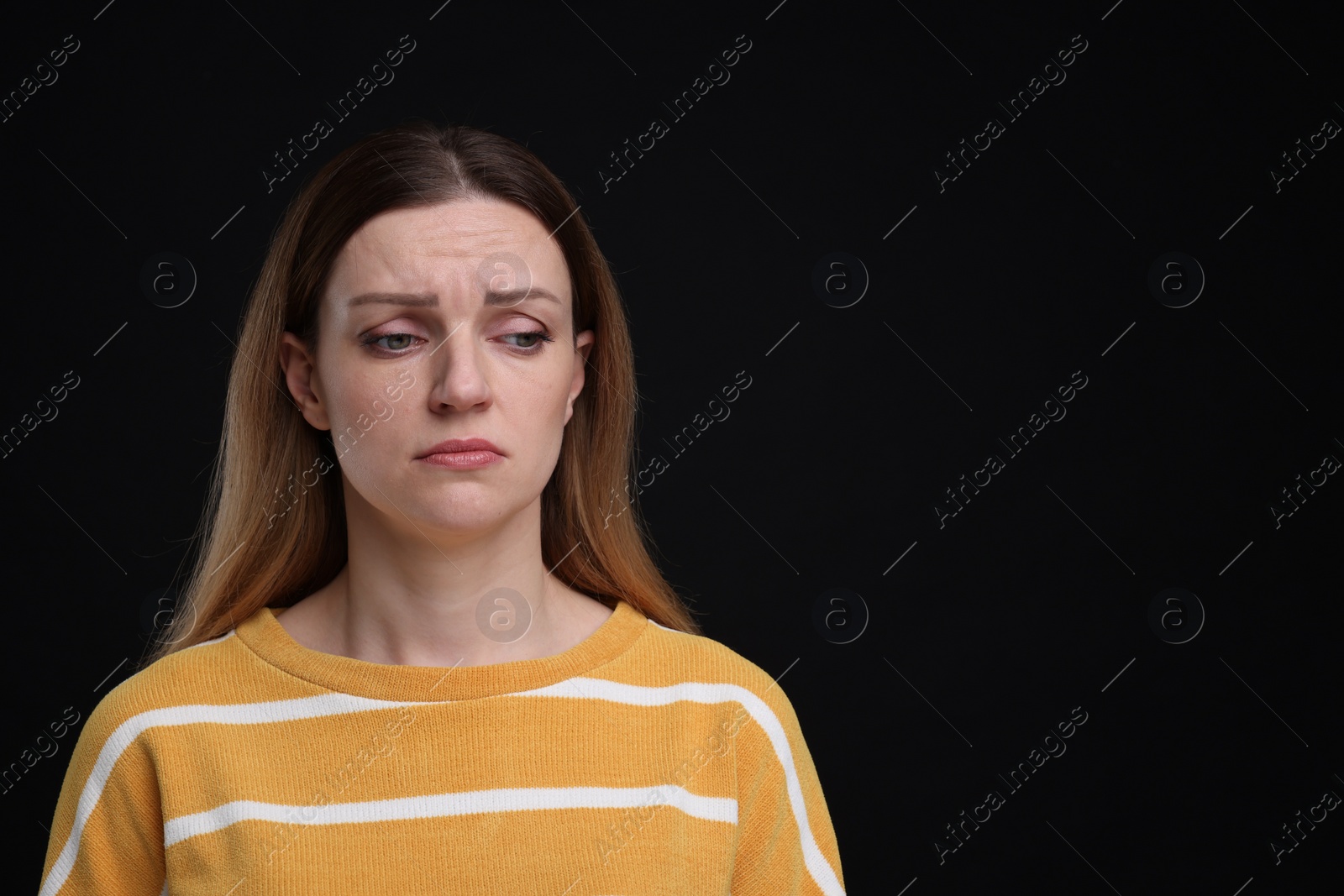 Photo of Portrait of sad woman on black background, space for text