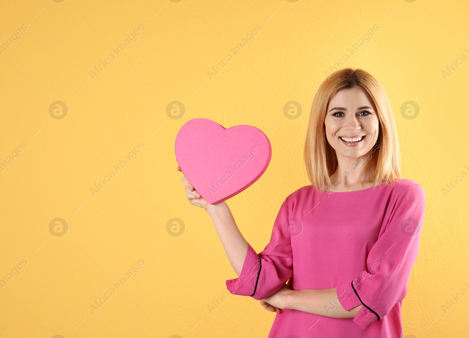 Photo of Beautiful woman with heart shaped box on color background. Space for text