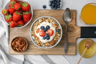 Tasty granola, yogurt and fresh berries served on light table, flat lay. Healthy breakfast