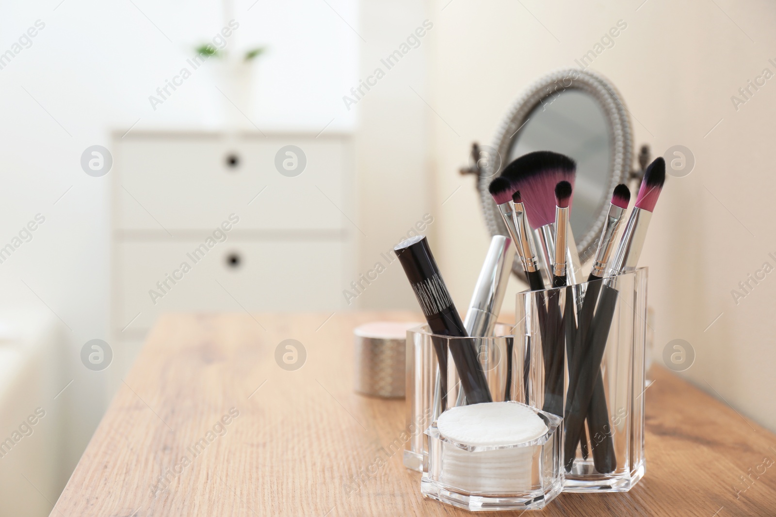 Photo of Organizer with makeup cosmetic products and mirror on table. Space for text