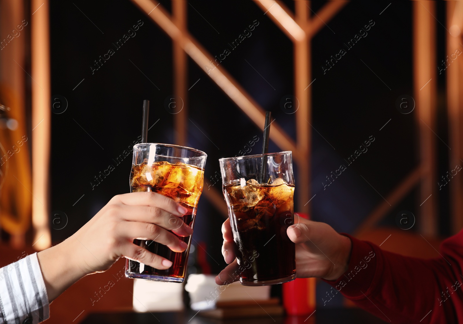 Photo of Young couple with glasses of refreshing cola at table indoors, closeup