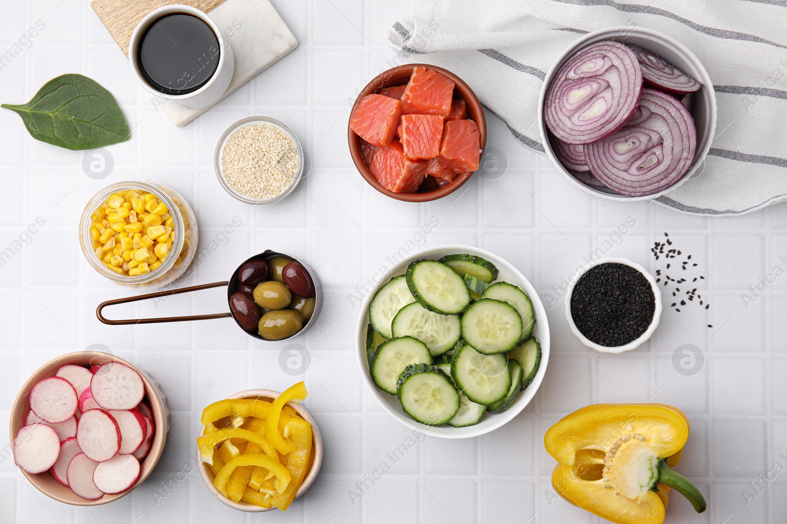 Photo of Ingredients for poke bowl on white checkered table, flat lay