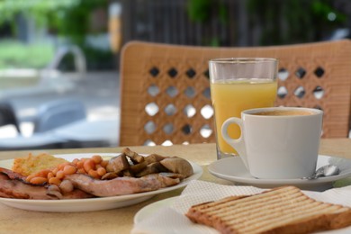 Photo of Delicious breakfast with fried meat and vegetables served on beige table in cafe