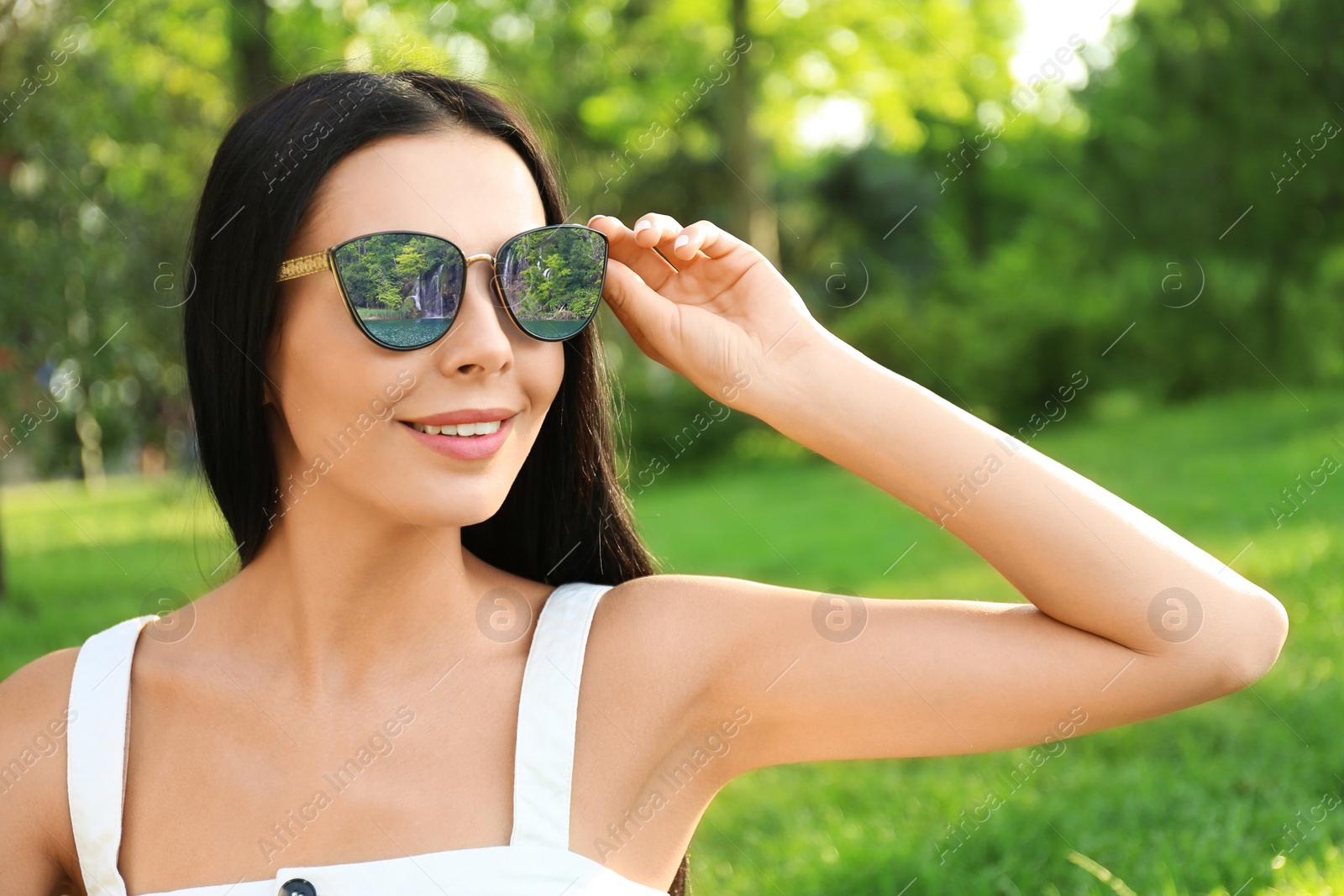 Image of Happy woman on vacation. Beautiful waterfall and lake mirroring in her sunglasses