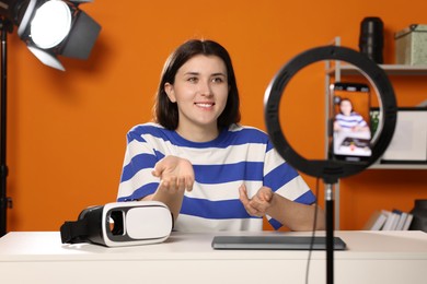 Smiling technology blogger recording video review about virtual reality headset at home