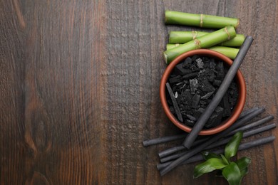 Photo of Fresh bamboo and charcoal on wooden table, flat lay. Space for text