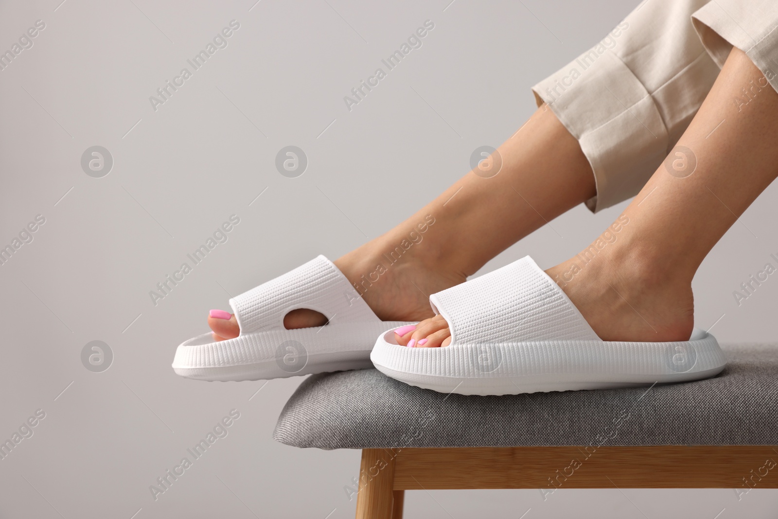 Photo of Woman wearing comfortable rubber slippers on grey background, closeup