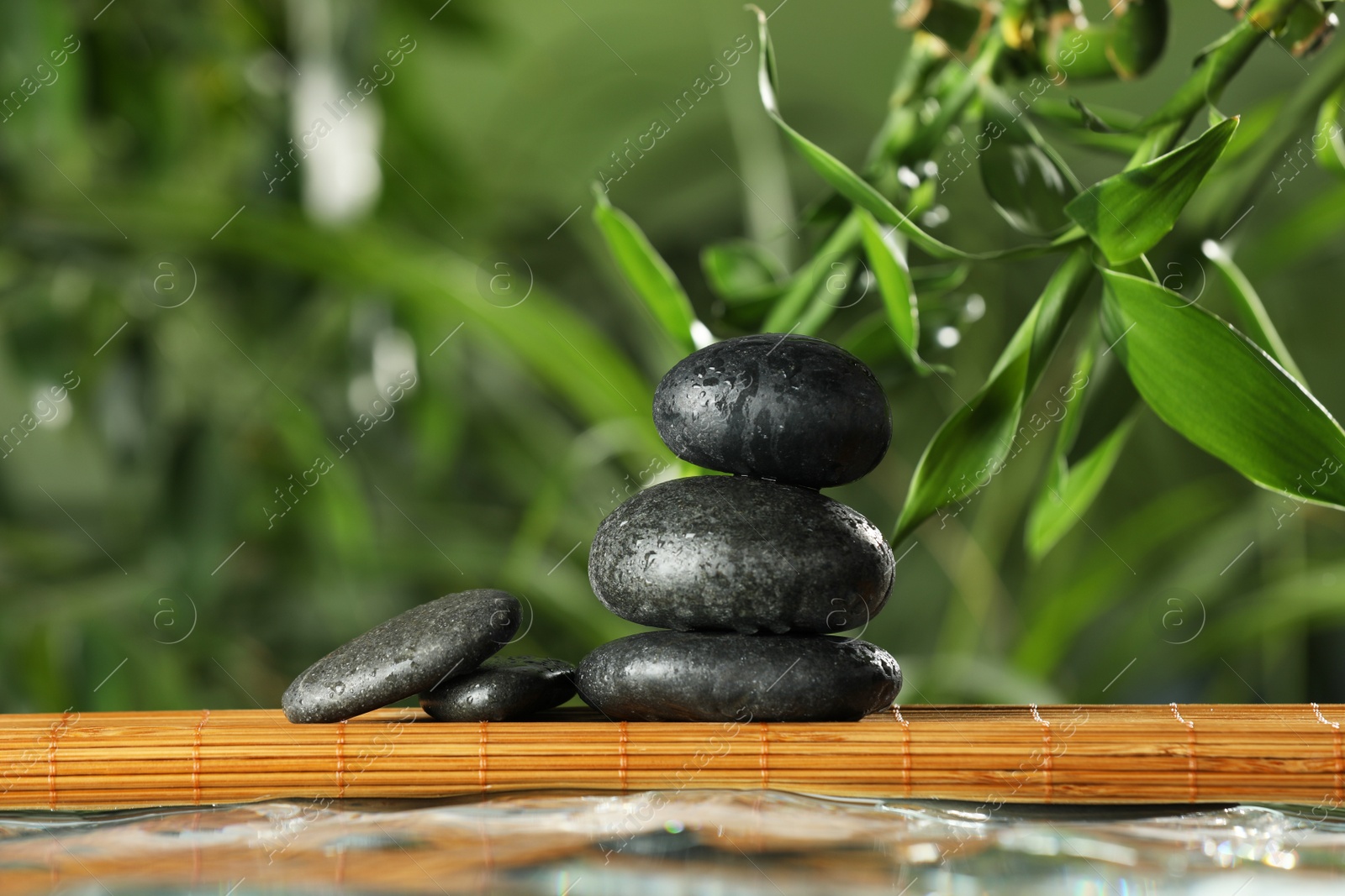 Photo of Stacked stones on bamboo mat over water against blurred background