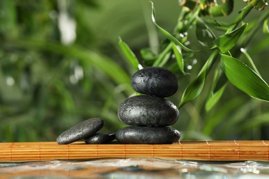 Photo of Stacked stones on bamboo mat over water against blurred background