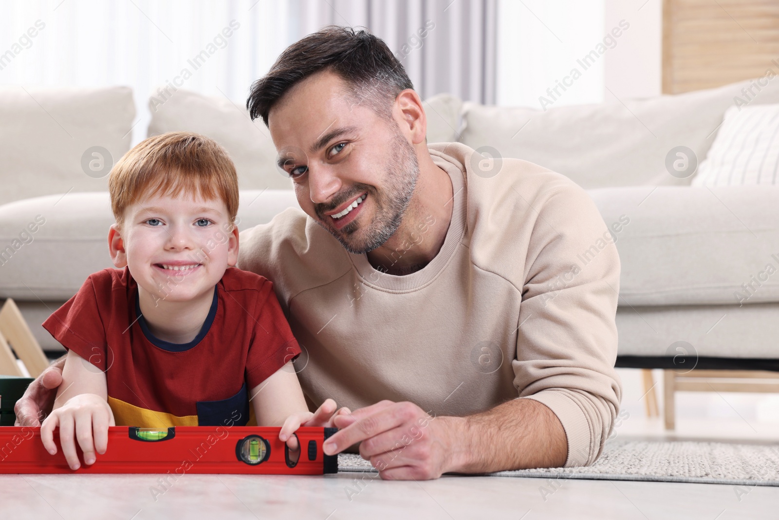 Photo of Father and son with bubble level at home. Repair work