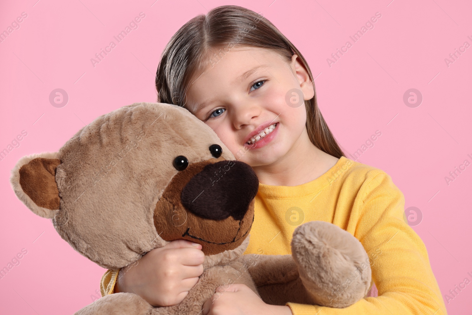 Photo of Cute little girl with teddy bear on pink background