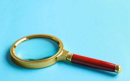 Photo of Closeup view of magnifier glass on light blue background, space for text. Find keywords concept