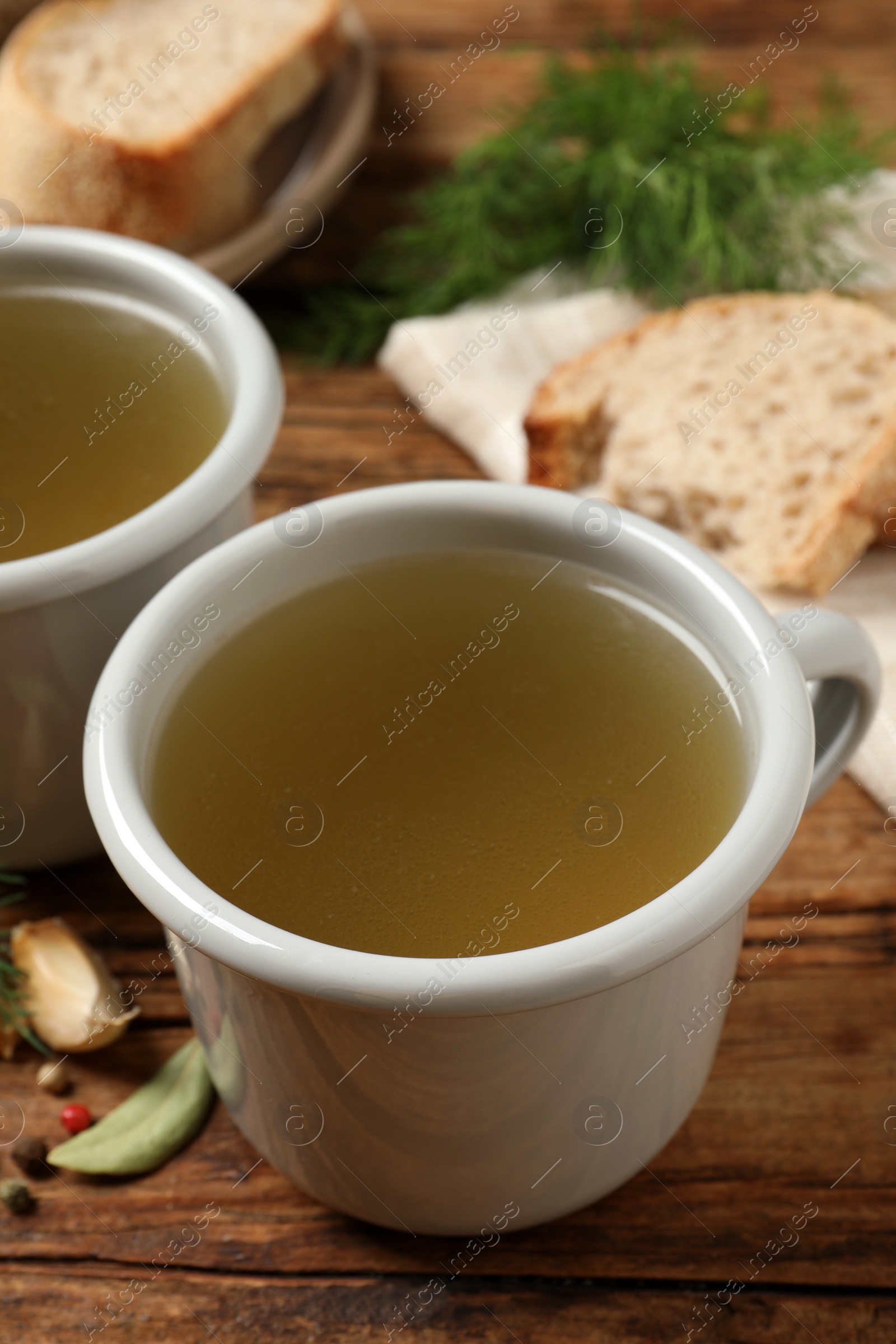 Photo of Hot delicious bouillon in cups on wooden table, closeup